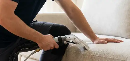 Professional upholstery cleaner deep-cleaning a fabric sofa with a handheld extraction tool, San Antonio, TX.